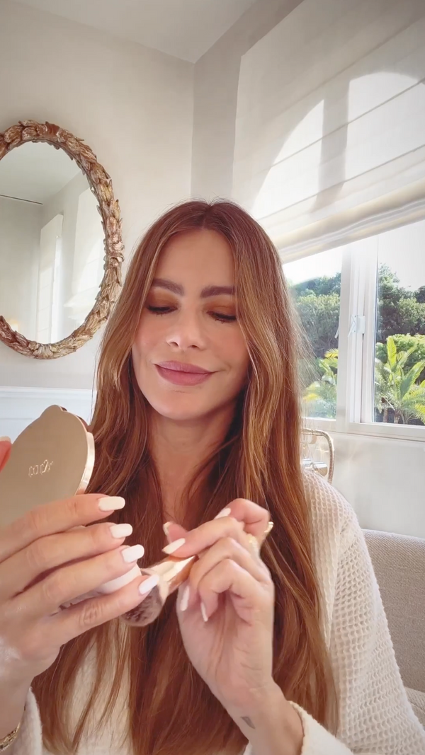 Sofia vergara Holding compact and a makeup brush